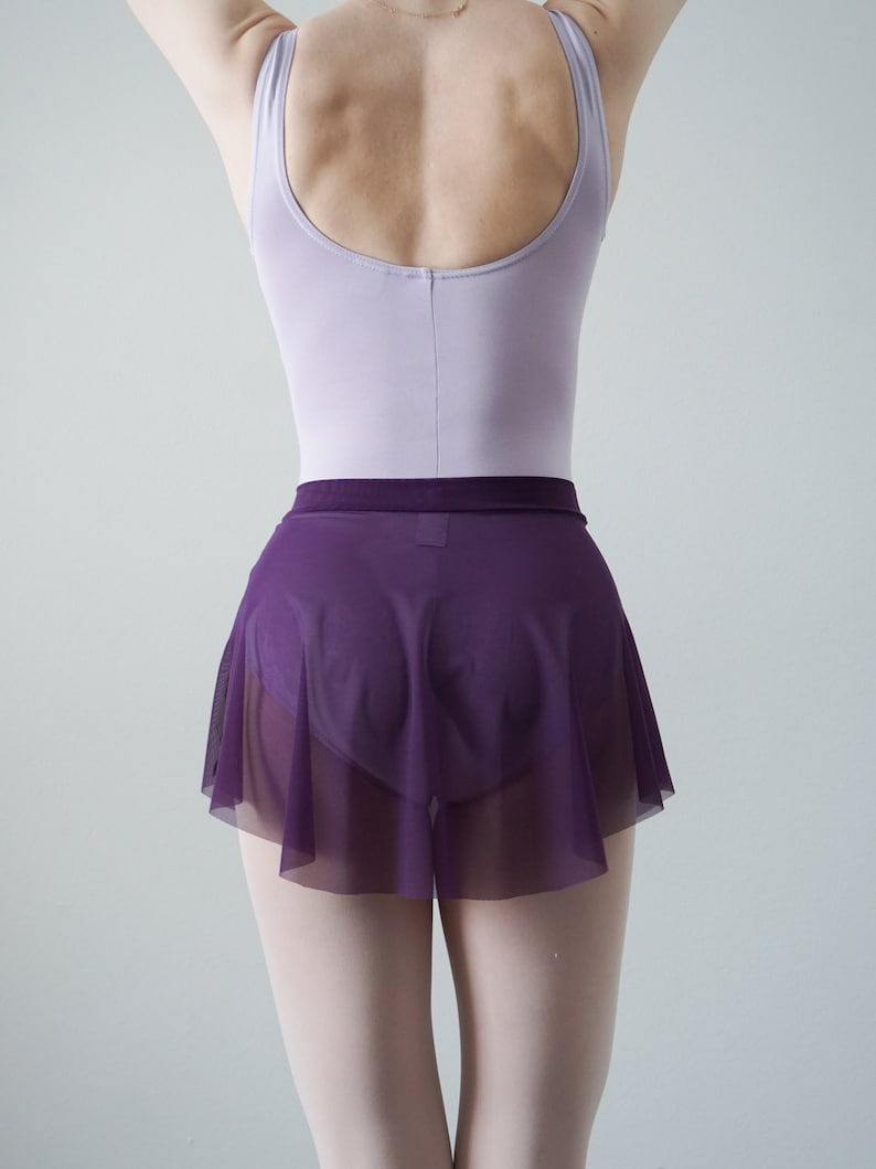 Op de afbeelding: Een paarse mesh dansschoen met daaronder een lavendelkleurig maillot. De rok is geplooid bij de taille en heeft een gerimpelde zoom.