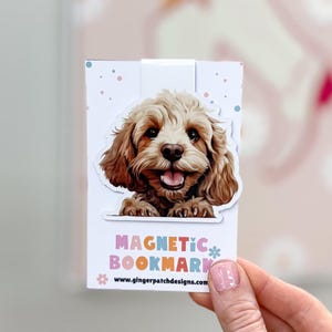May include: A white magnetic bookmark with a brown and white dog peeking over the top. The bookmark has the text "MAGNETIC BOOKMARK" in colorful letters and the website "www.gingerpatchdesigns.com" printed below.