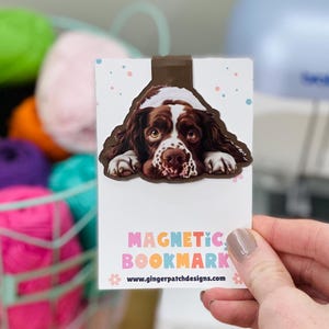 May include: A brown and white Springer Spaniel dog peeks over the top of a magnetic bookmark. The bookmark is white with colorful polka dots and the text "Magnetic Bookmark" and "www.gingerpatchdesigns.com".