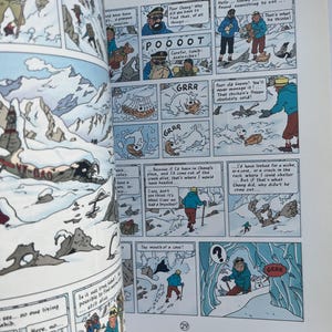 May include: Open book with comic strip panels depicting a snowy mountain scene. Characters in winter attire are shown interacting with each other and the environment. Text bubbles contain dialogue and sound effects like "GRRR".