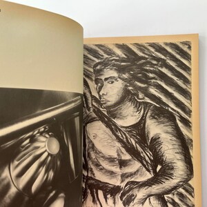 K&ouml;nnte beinhalten: Ein offenes Buch mit zwei Bildern. Die linke Seite zeigt eine Schwarz-Wei&szlig;-Fotografie eines metallischen Objekts mit einem kreisf&ouml;rmigen Element. Die rechte Seite zeigt eine Kohlezeichnung einer Person, die einen Speer h&auml;lt.