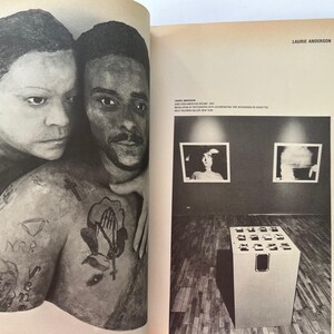 K&ouml;nnte beinhalten: Schwarz-Wei&szlig;-Kunstwerk von zwei Personen, von denen eine die andere umarmt. Die umarmte Person hat T&auml;towierungen auf Arm und Brust. Das Bild stammt aus einem Buch mit Text auf der rechten Seite. Der Text lautet "Laurie Anderson".