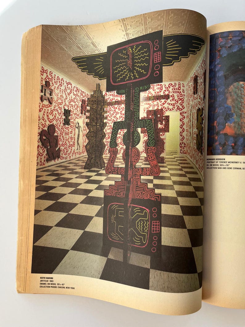 K&ouml;nnte beinhalten: Eine Magazinseite mit einer Kunstinstallation von Keith Haring. Die Installation umfasst gro&szlig;e, farbenfrohe, abstrakte Skulpturen in einem Raum mit einem schwarz-wei&szlig; karierten Boden und W&auml;nden, die mit rot-wei&szlig;en Mustern bedeckt sind.
