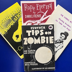May include: Four vintage magic books are displayed against a blue background. Titles include "Sponge Ball Manipulation," "Rope Eternal," "The String Book," and "Further Tips on Zombie." The books feature illustrations and text in various colors.