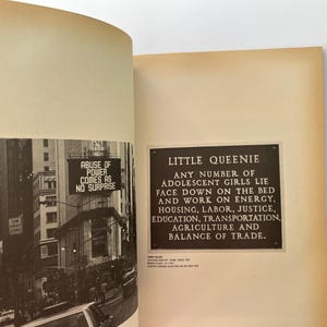 K&ouml;nnte beinhalten: Offenes Buch mit zwei Seiten. Eine Seite zeigt ein Schwarz-Wei&szlig;-Foto einer Stadtstra&szlig;e mit dem Text "ABUSE OF POWER COMES AS NO SURPRISE". Die andere Seite hat eine Tafel mit dem Text "LITTLE QUEENIE".