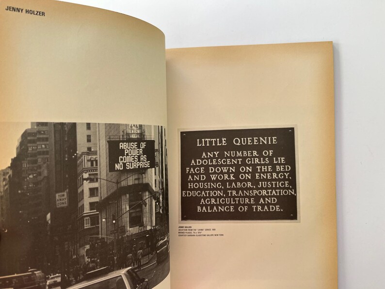 K&ouml;nnte beinhalten: Offenes Buch mit zwei Seiten. Eine Seite zeigt ein Schwarz-Wei&szlig;-Foto einer Stadtstra&szlig;e mit dem Text "ABUSE OF POWER COMES AS NO SURPRISE". Die andere Seite hat eine Tafel mit dem Text "LITTLE QUEENIE".