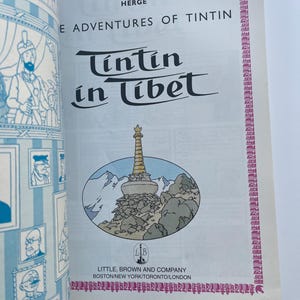 May include: A vintage copy of "Tintin in Tibet" by Herg&eacute;. The cover features the title in a stylized font, with an illustration of a mountain scene and a pagoda. The book is published by Little, Brown and Company.