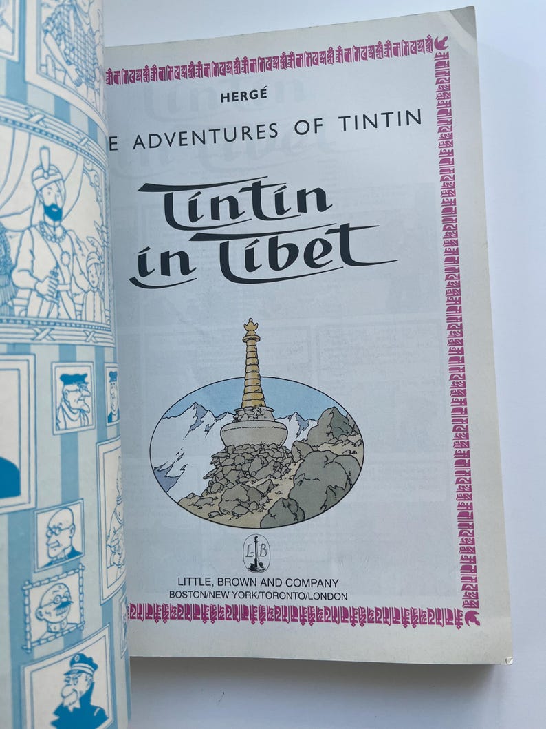 May include: A vintage copy of "Tintin in Tibet" by Herg&eacute;. The cover features the title in a stylized font, with an illustration of a mountain scene and a pagoda. The book is published by Little, Brown and Company.