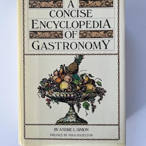 May include: A Concise Encyclopedia of Gastronomy book. The cover features a decorative border and the title in bold, black text. Below the title is a detailed illustration of a fruit-filled bowl. The author's name and preface are also visible.