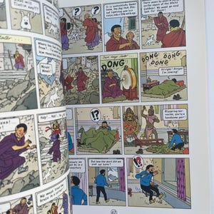 May include: A comic book page featuring panels with illustrations and speech bubbles. The panels depict scenes with characters in robes, a dog, and text. The page includes the number 47.