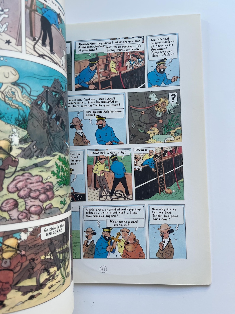 May include: A comic book page featuring panels from a Tintin adventure. The panels depict various scenes with characters in sailor uniforms, a diver, and underwater scenes. Text bubbles contain dialogue.