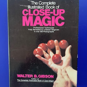 May include: A vintage book titled "The Complete Illustrated Book of CLOSE-UP MAGIC" with a black cover and pink lettering. The cover features a hand holding several red balls. The author's name is Walter B. Gibson.