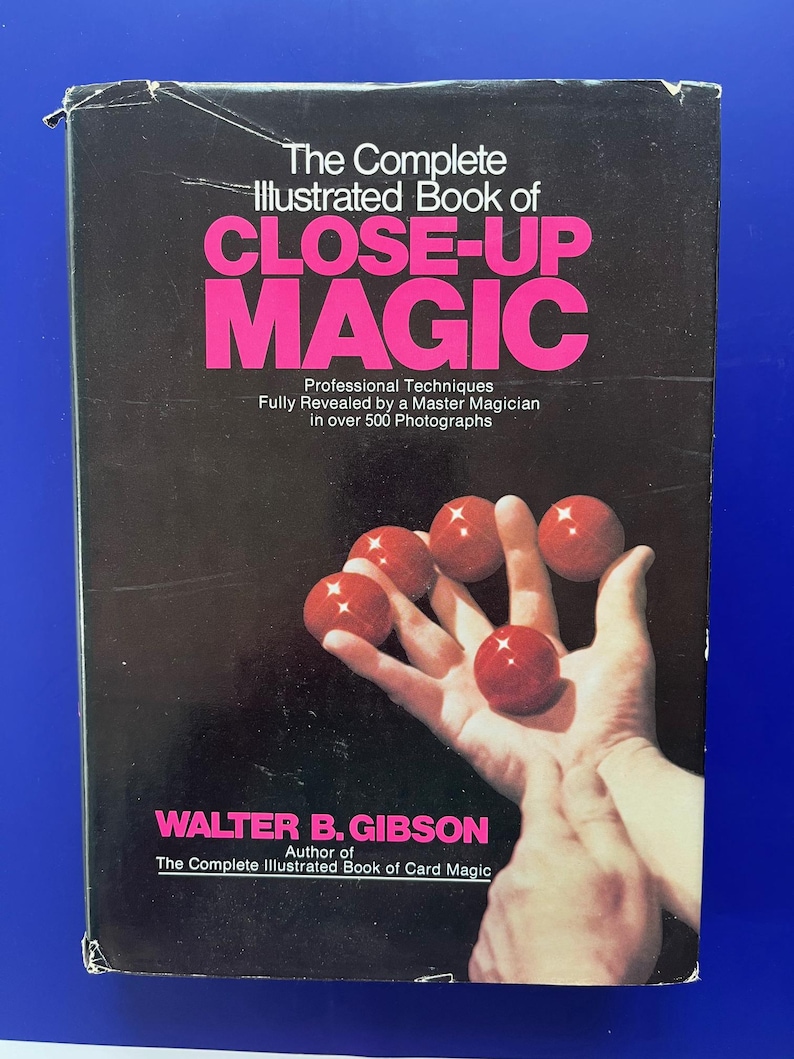 May include: A vintage book titled "The Complete Illustrated Book of CLOSE-UP MAGIC" with a black cover and pink lettering. The cover features a hand holding several red balls. The author's name is Walter B. Gibson.