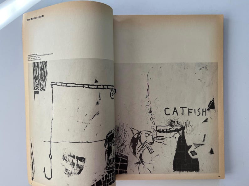 K&ouml;nnte beinhalten: Offene Buchseiten mit Schwarz-Wei&szlig;-Illustrationen. Eine Seite zeigt einen Angelhaken und abstrakte Formen. Die andere Seite zeigt das Wort "CATFISH" und eine Zeichnung einer katzenartigen Figur.