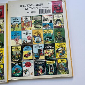 May include: A collection of Tintin comic books featuring various adventures, including "Tintin in America" and "The Black Island." The covers display colorful illustrations and the title "The Adventures of Tintin" by Herg&eacute;.
