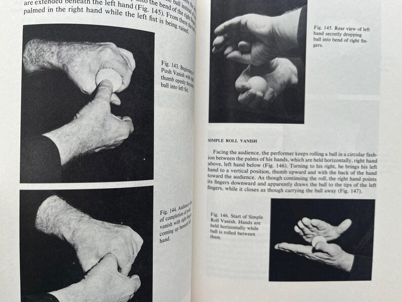May include: Black and white illustrations from a magic book demonstrate the Simple Roll Vanish. The images show hands manipulating a small ball, with text describing the steps of the trick.