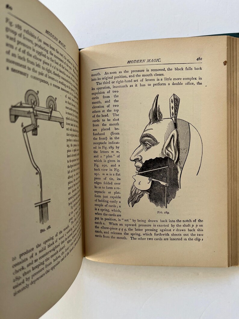 K&ouml;nnte beinhalten: Offenes Buch mit Text und Illustrationen. Die rechte Seite zeigt eine detaillierte Zeichnung einer teufelartigen Figur mit einer mechanischen Vorrichtung an ihrem Mund. Der Text lautet "MODERN MAGIC."