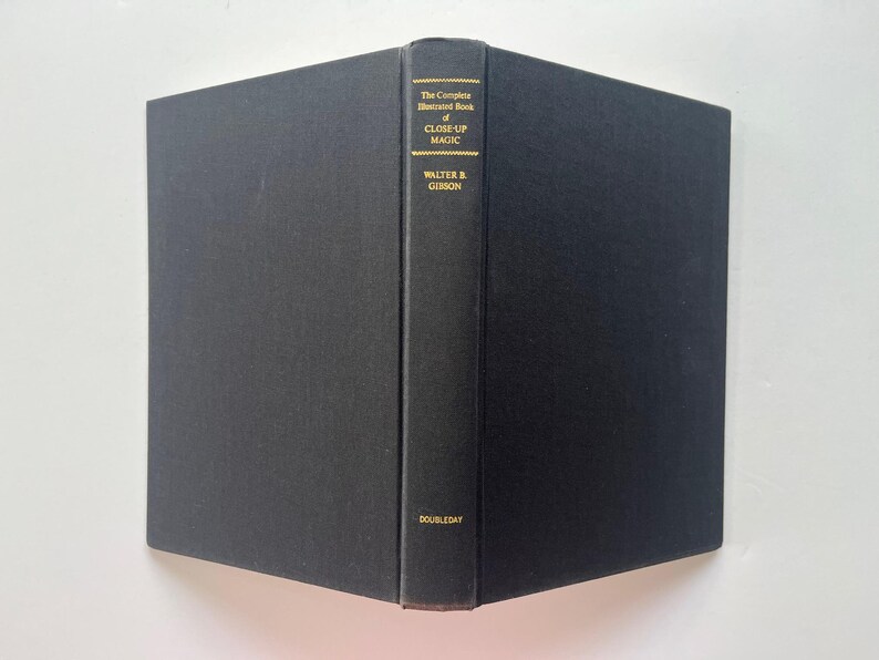 May include: A hardcover book titled "The Complete Illustrated Book of Close-Up Magic" by Walter B. Gibson. The book has a black cover and spine with gold lettering. The publisher's name, Doubleday, is printed at the bottom of the spine.