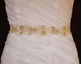 May include: A white satin wedding dress with a gold beaded and lace sash.