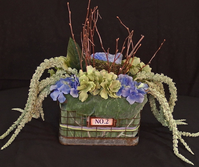 Floral arrangement with blue bird nest blue and green theme with old time wire basket large lettuce leaves floral hydrangea basket