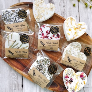 Può includere: Una collezione di bombe da bagno a forma di cuore, confezionate singolarmente. Le bombe sono decorate con lavanda, petali di rosa e avena. Ogni confezione riporta la scritta "Bath Bomb 100% Natural Vegan".