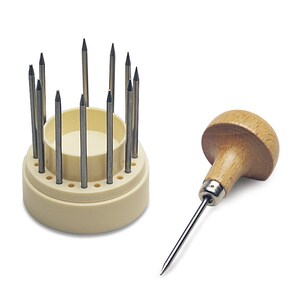 May include: A set of 12 metal tools with wooden handles, used for jewelry making. The tools are arranged in a white plastic holder with a circular base.