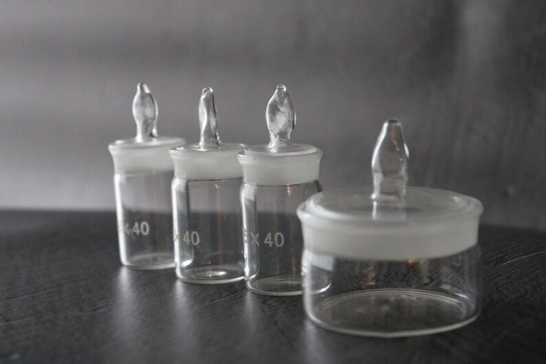 May include: Four clear glass bottles with frosted glass lids and glass stoppers. The bottles are labelled with the number 40.