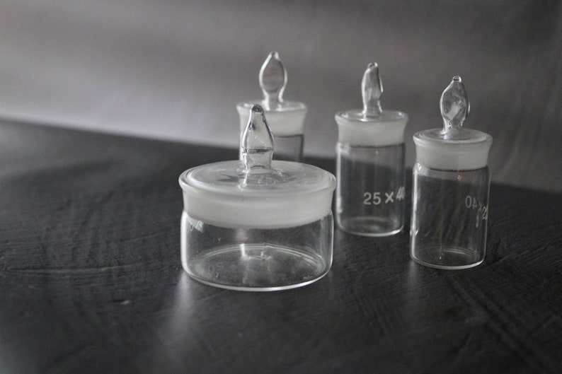May include: Four clear glass bottles with glass stoppers. The bottles have a frosted glass top and are labelled with the text "25 x 4" and "04/12".