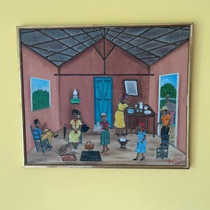 Puede incluir: Una pintura enmarcada representa una escena doméstica con varias figuras dentro de una estructura simple. La obra de arte presenta una paleta de colores cálidos, con tonos de marrón, rojo y amarillo que dominan el interior. Las figuras visten ropa colorida.