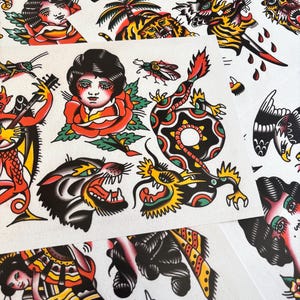 Peut inclure: Une collection de planches de tatouage flash présentant des motifs traditionnels, notamment une tête de panthère noire, un dragon enroulé, un visage humain dans une rose rouge, un diable rouge jouant du banjo, une sauterelle, une mouche et divers oiseaux.