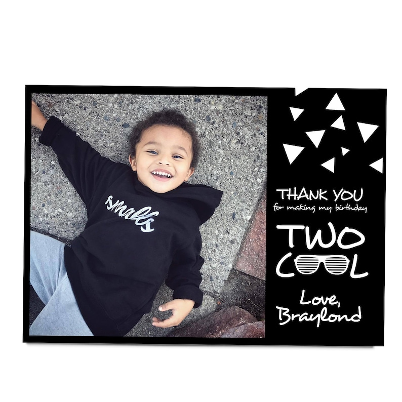 May include: A black and white thank you card with a photo of a young child wearing a black hoodie with the word "smalls" in white lettering. The text on the card reads "Thank you for making my birthday two cool. Love, Braylond."