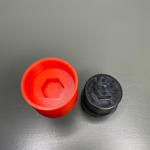 May include: A red plastic cap with a hexagonal opening and a black plastic cap with a hexagonal opening.