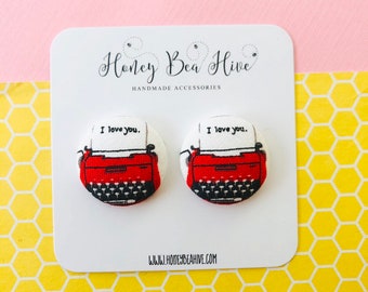 May include: A pair of red and white fabric button earrings with a vintage typewriter design. The typewriter has the text "I love you." printed on the paper.