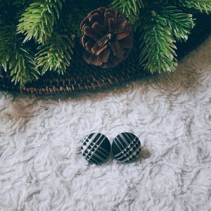 May include: A pair of black and white plaid fabric button earrings.