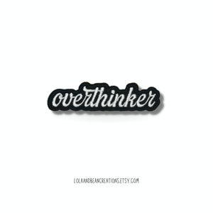 May include: White embroidered "overthinker" text on a black iron-on patch.