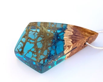 May include: A blue and brown resin pendant with a silver chain. The resin has a unique pattern of brown lines and swirls.