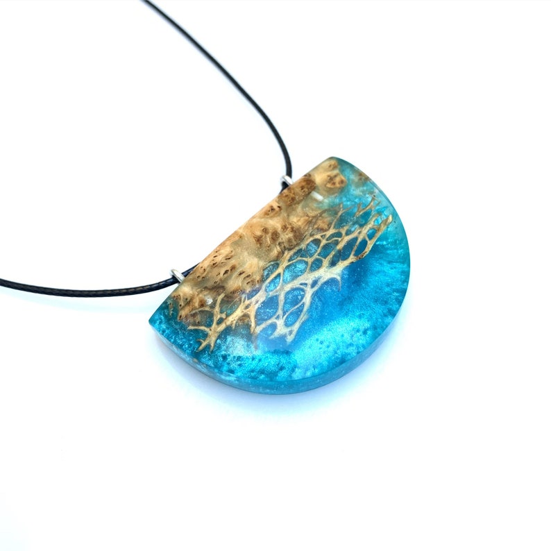 May include: A turquoise and brown resin pendant with a wood grain pattern, hanging from a black cord necklace.