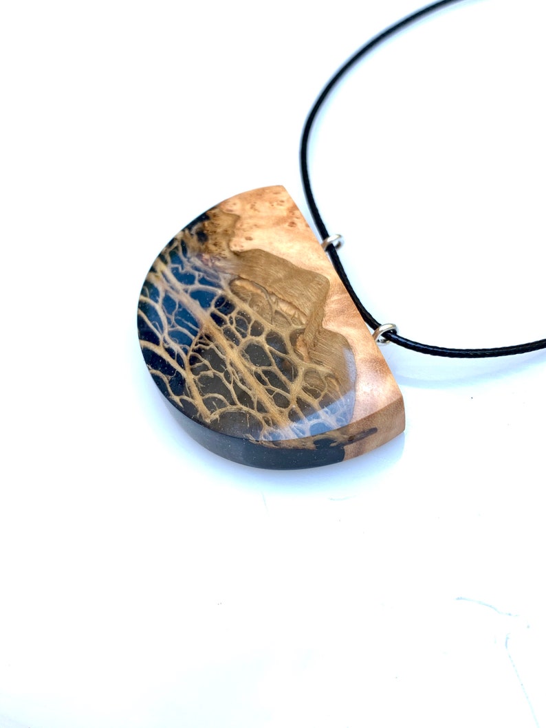 May include: A black and brown wood and resin pendant necklace with a black cord.