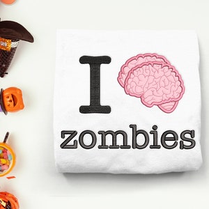 May include: White t-shirt with black text that reads "I love zombies" and a pink brain graphic.