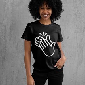 May include: A black t-shirt featuring a white graphic of two hands clapping together. The graphic is a simple line drawing.