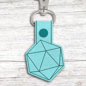 May include: A teal keychain with a geometric icosahedron design, outlined in black. It has a matching teal strap and a silver clasp. The design is similar to a D20 die, often used in tabletop games.