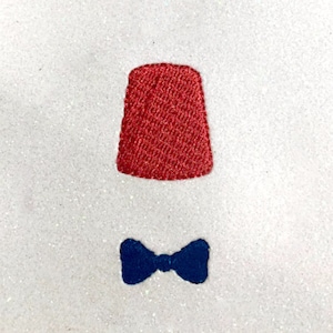 May include: A red fez with a blue bow tie. The fez is a traditional hat worn by men in some cultures.