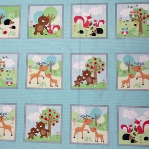 May include: A blue fabric with a repeating pattern of framed illustrations of animals in a forest setting. The animals include bears, deer, squirrels, and hedgehogs. The illustrations are surrounded by a light blue background with a white border.
