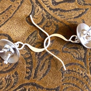 May include: A pair of silver earrings with a circular design. The earrings have a simple, elegant style.