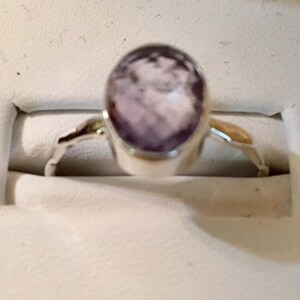Pu&ograve; includere: Un anello d'argento con una pietra ovale di colore viola chiaro.