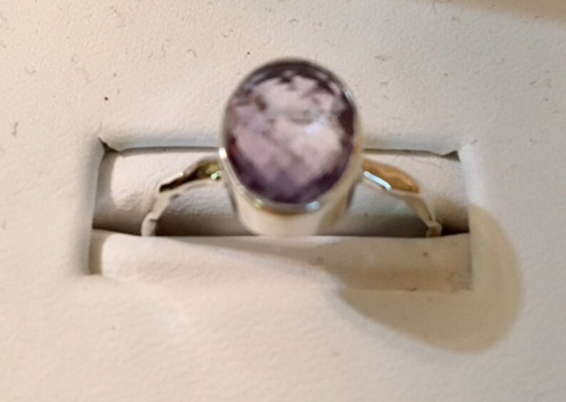 Pu&ograve; includere: Un anello d'argento con una pietra ovale di colore viola chiaro.