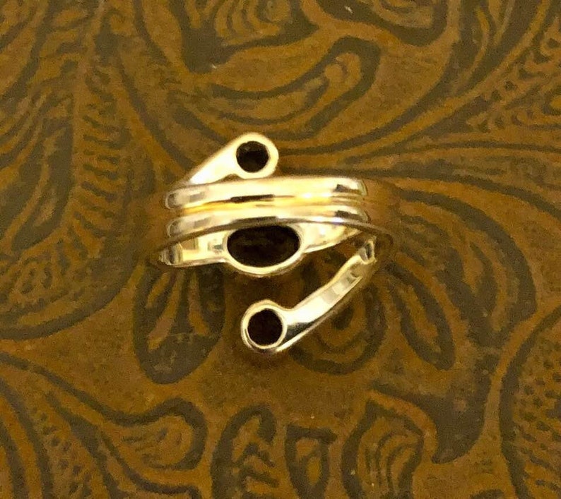 Peut inclure: Bague en or avec trois pierres pr&eacute;cieuses noires. La bague est con&ccedil;ue avec une bande torsad&eacute;e et une forme unique.