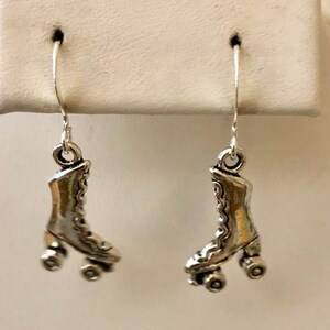 May include: A pair of silver roller skate earrings. Each earring features a detailed design of a roller skate with four wheels.