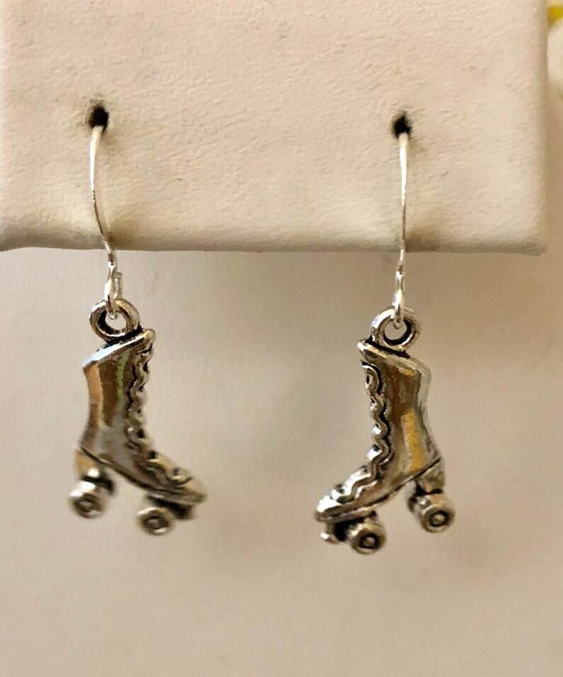 May include: A pair of silver roller skate earrings. Each earring features a detailed design of a roller skate with four wheels.