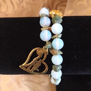 May include: A double-strand bracelet with light blue and green gemstone beads and a gold heart charm.